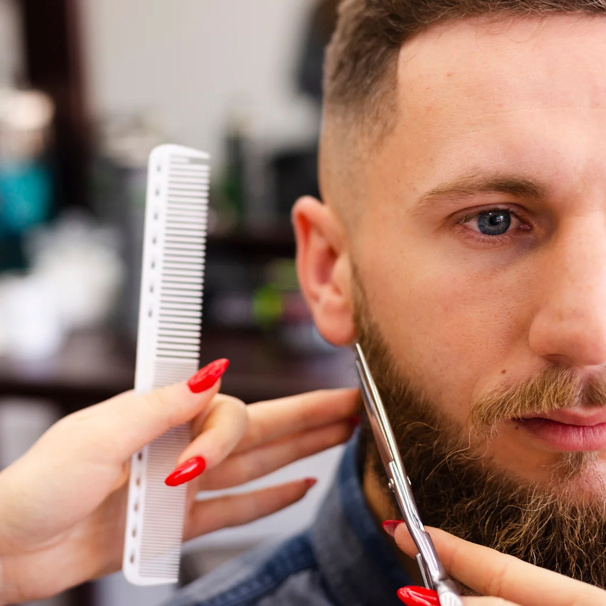 Barberka przycinająca brodę klienta podczas zabiegu w barbershopie